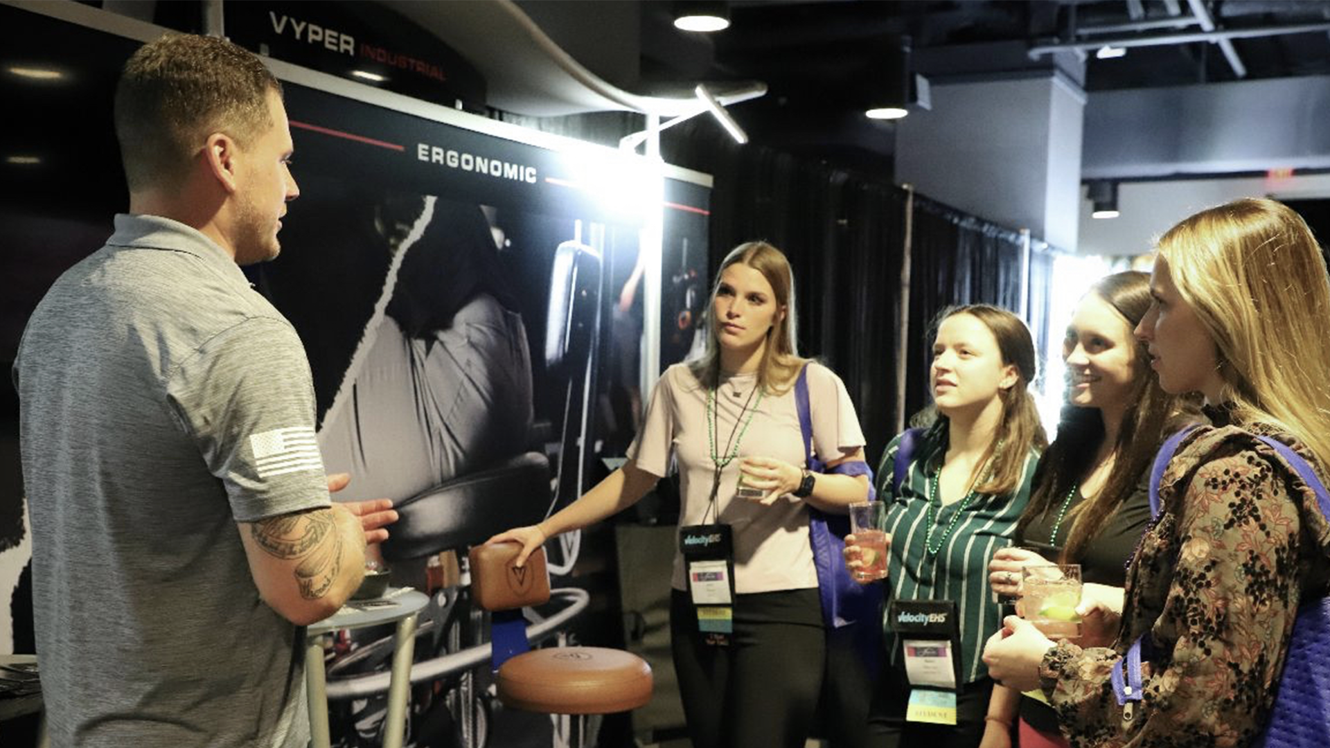 guy in gray shirt address four women at a conference