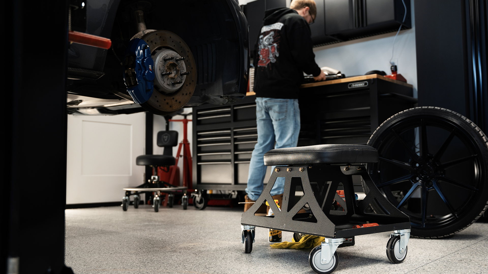 Man in black shirt and jeans working in garage with Vyper chair in the foreground