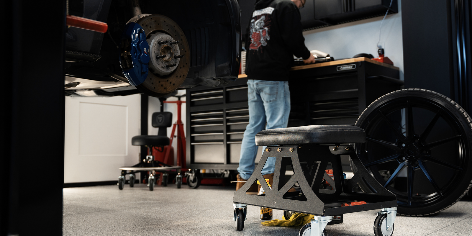 Man in black shirt and jeans working in garage with Vyper chair in the foreground