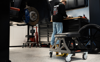 Man in black shirt and jeans working in garage with Vyper chair in the foreground
