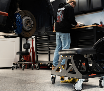 Man in black shirt and jeans working in garage with Vyper chair in the foreground