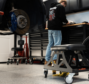 Man in black shirt and jeans working in garage with Vyper chair in the foreground